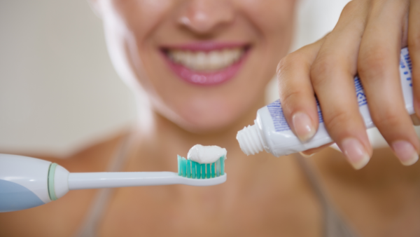 Woman holding toothpaste and a toothbrush